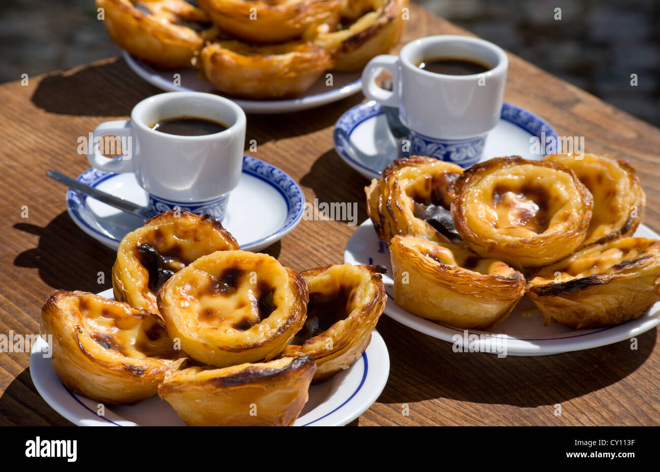 Pasteis de Nata or Pasteis de Belem; custard tarts, on a café table outdoors with bica coffees; Belém, Lisbon, Portugal Stock Photo