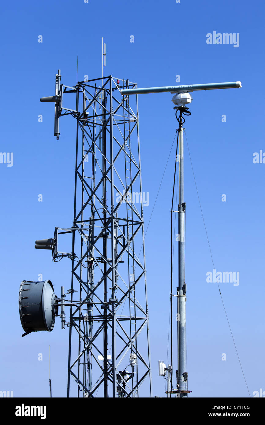 A group of radio masts and point-to-point microwave communications and radar systems on various other communication towers. Stock Photo