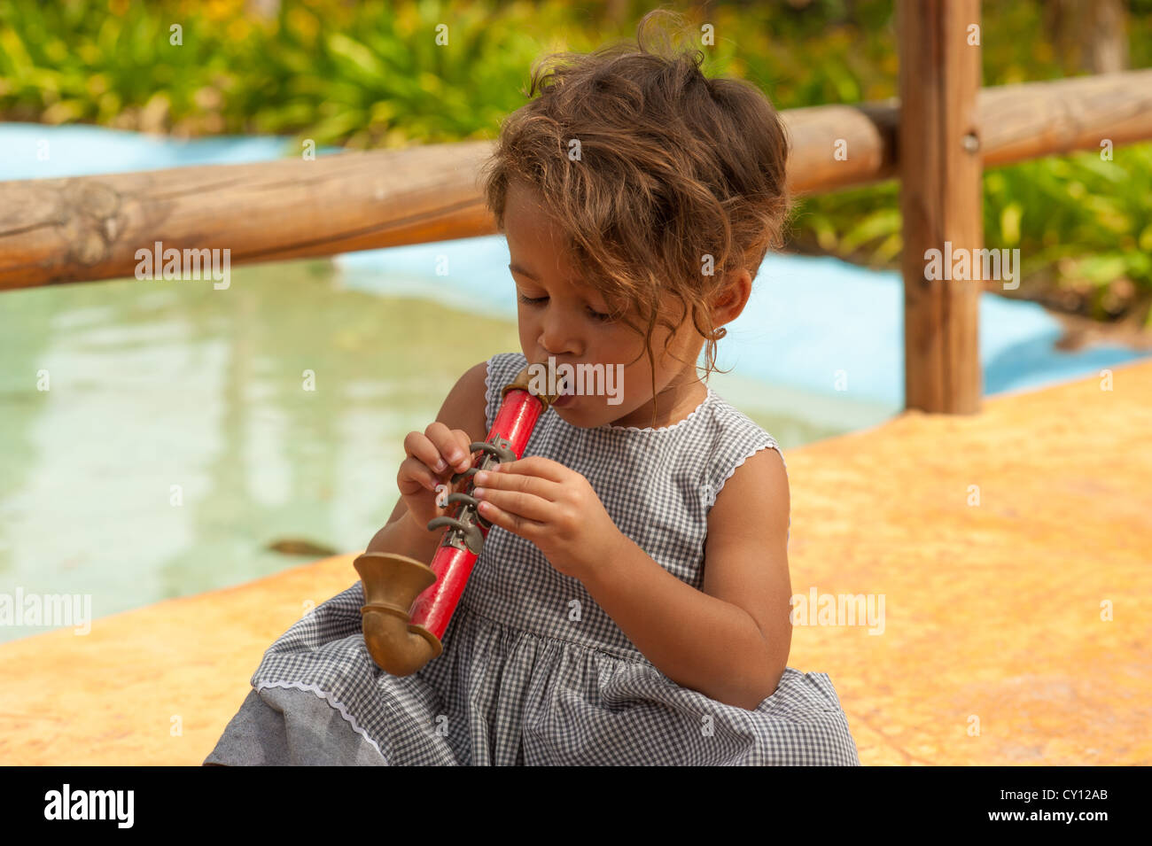 Cute Hispanic girl playing with a toy saxophone Stock Photo