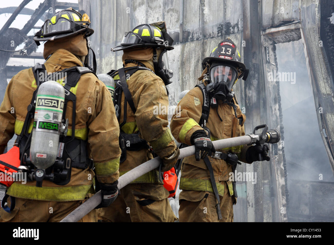 Firewoman and firefighters putting out a fire in an industrial building ...