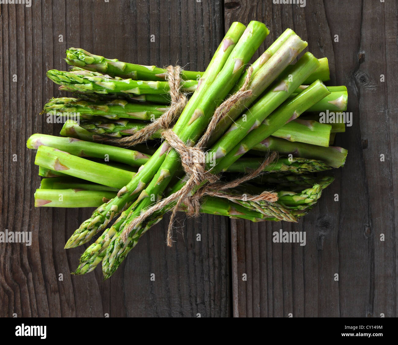 Bunches of asparagus tied with twine on a wood background. Overhead view in horizontal format. Stock Photo