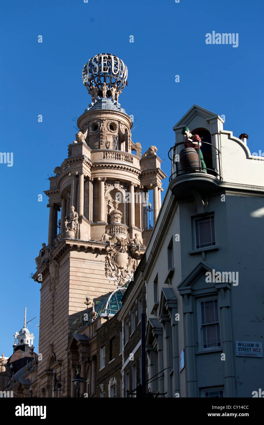 The London Coliseum Theatre & a Sculpture of a man & beer barrel on top The Chandos Pub. Trafalgar Square, London, UK. Stock Photo