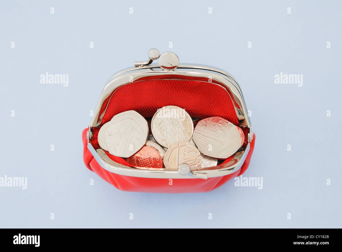 Red money coin purse open full of coins on a plain blue background from above. England, UK, Britain. Stock Photo