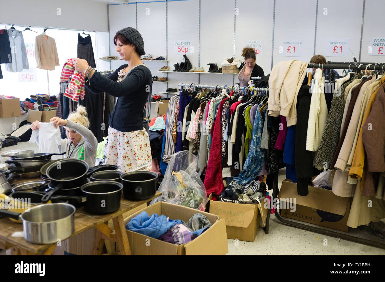 Women browsing racks of second hand clothes and goods on sale in a charity shop thrift store jumble sale uk Stock Photo