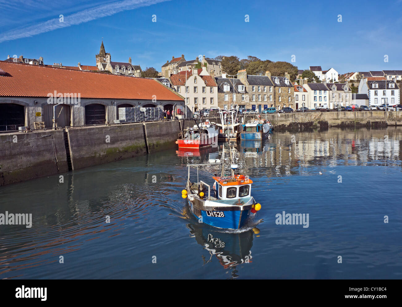 Fishing boat leaving Pittenweem harbour in Fife Scotland heading for the fishing grounds on a sunny autumn day. Stock Photo