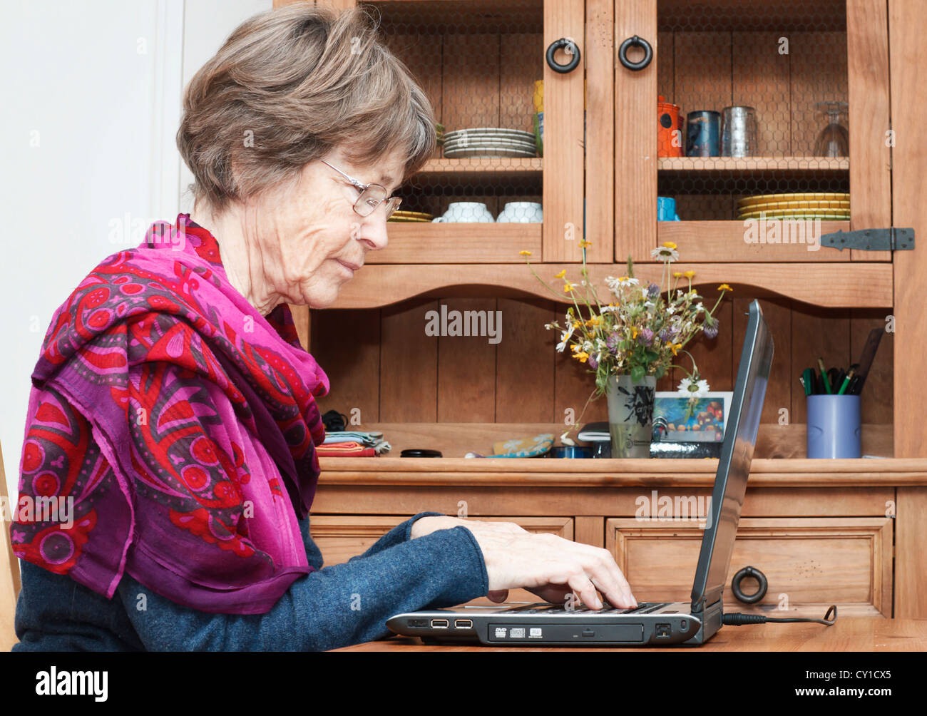 Senior woman using laptop at home, France. Stock Photo