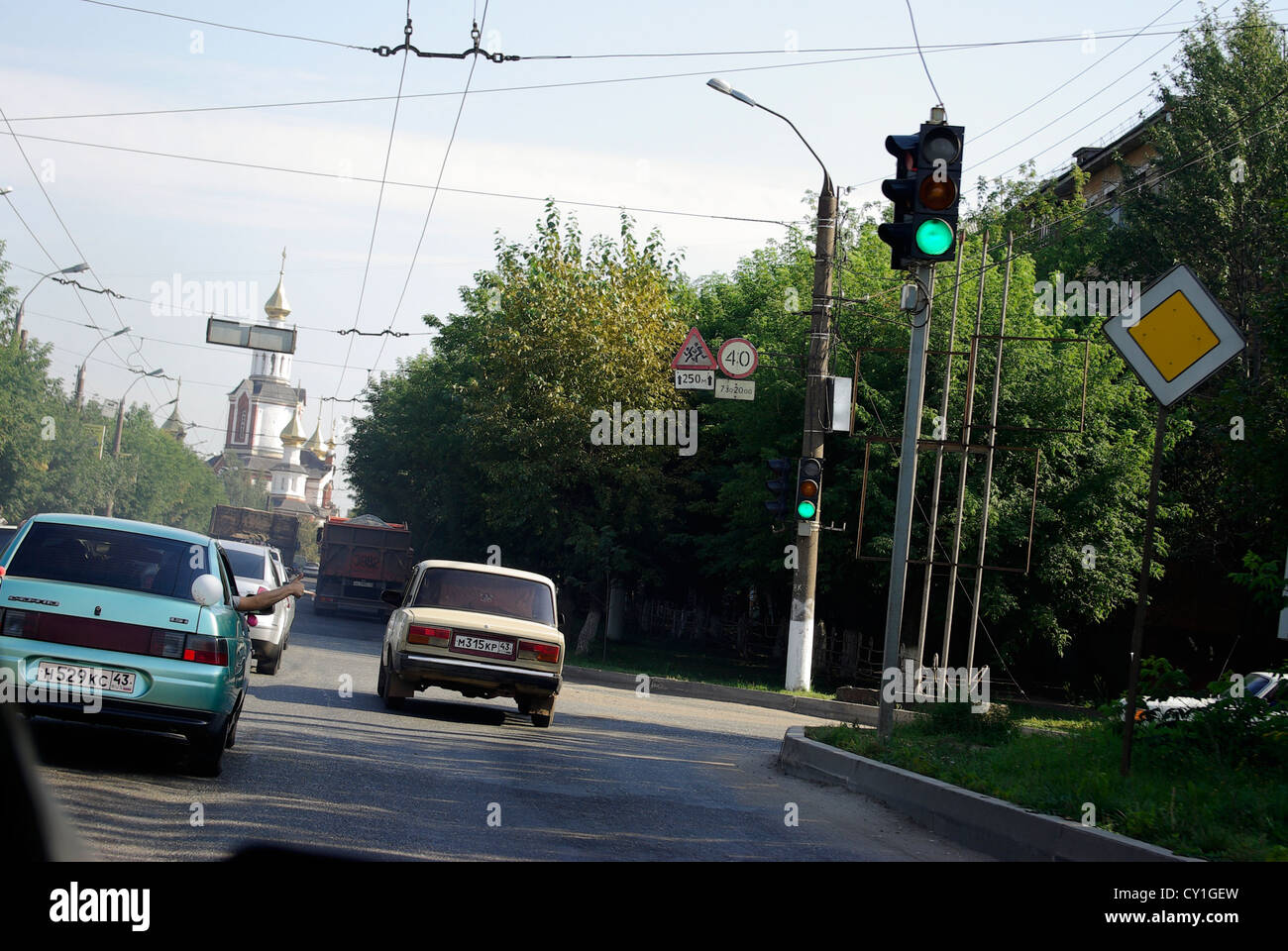 Cars drive along a typical street in Kirov Russia with an Orthodox church in the background Stock Photo
