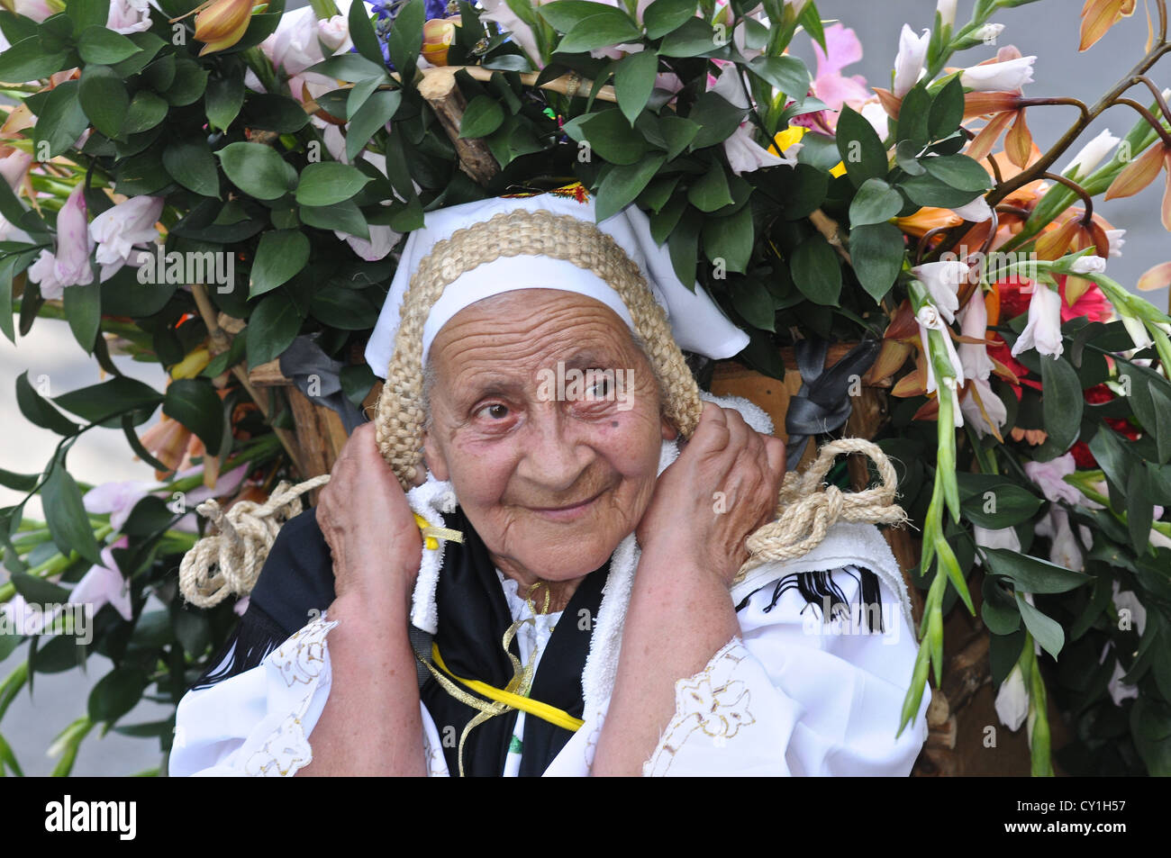 A peasant carries a heavy load of flowers from the mountains to sell. Stock Photo