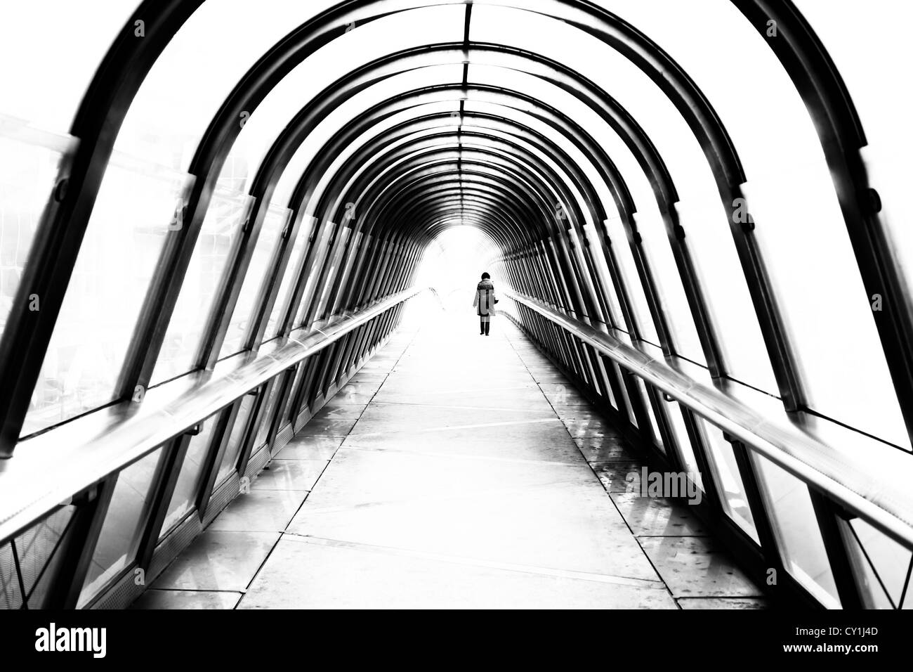 Lone female figure walking along modern foot bridge Stock Photo - Alamy