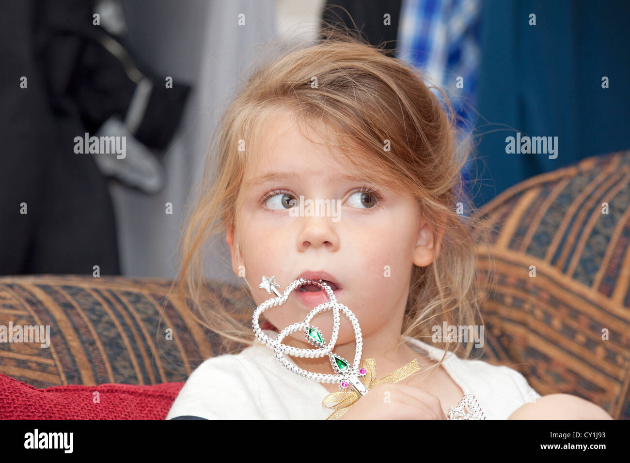 young child sat on sofa with toy wand Stock Photo