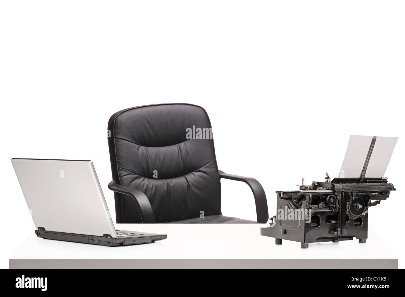 A laptop and an old fashioned typing machine on a table in modern office isolated on white Stock Photo