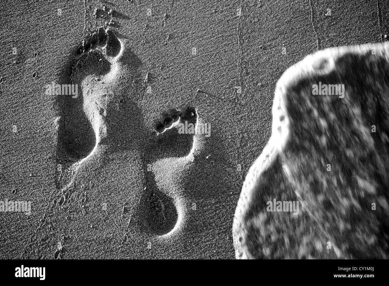 Two footprints in the sand, about to be erased Stock Photo Alamy