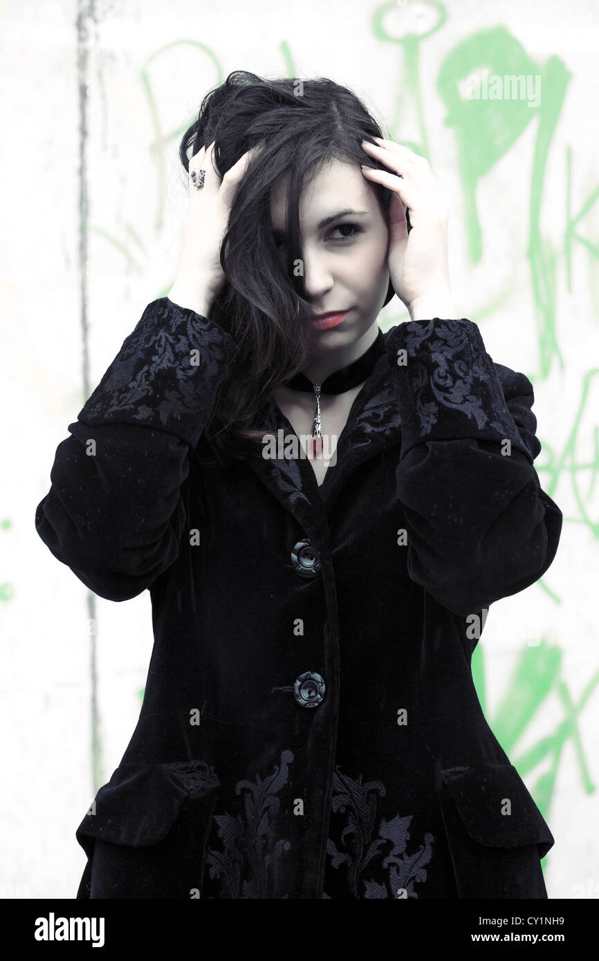 a woman in a black coat in front of a graffiti wall Stock Photo - Alamy