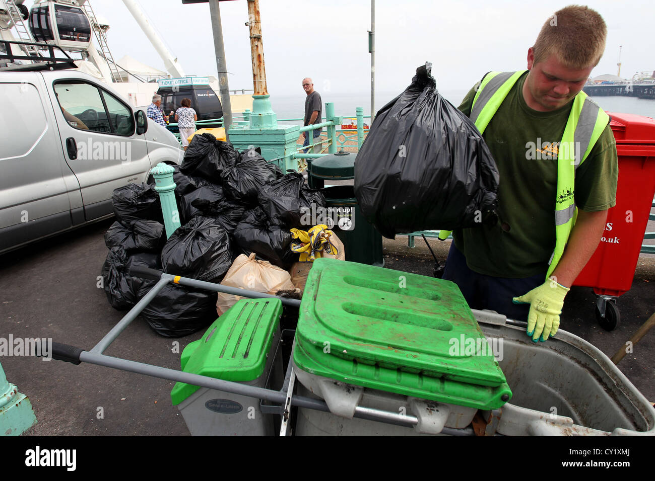A Council binman picking up all the rubbish from Brighton Beach close to the Brighton (Palace) Pier, East Sussex, UK. Stock Photo