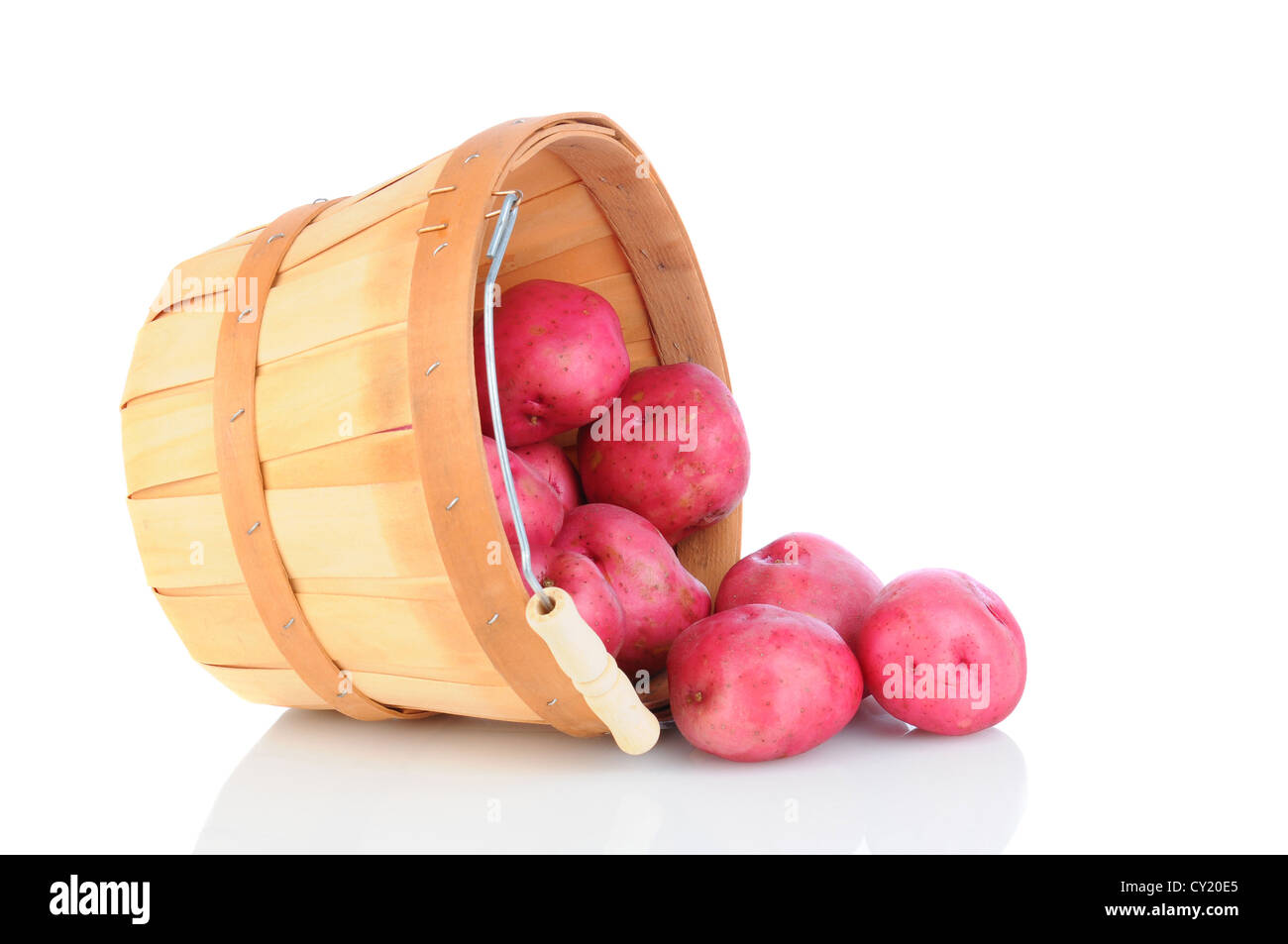 A basket of red potatoes tipped over and spilling onto the reflective surface. Horizontal format. Stock Photo