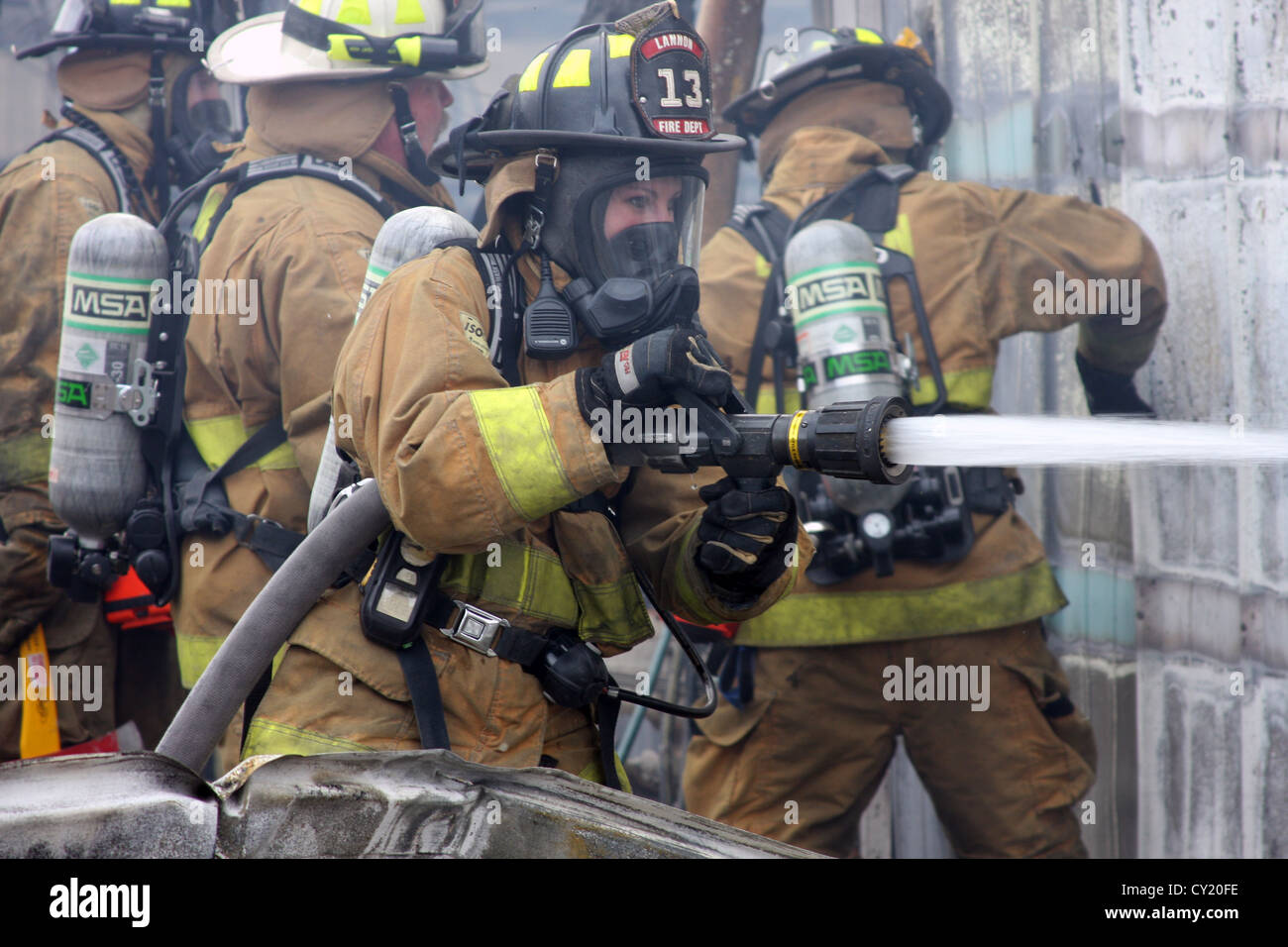 A woman firefighter pouring water on a fire in Wisconsin Stock Photo