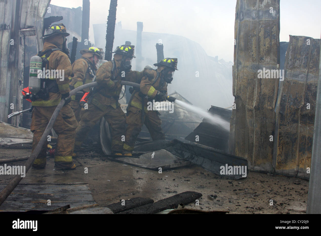 Firefighters at the scene of an industrial fire extinguishing the hot ...