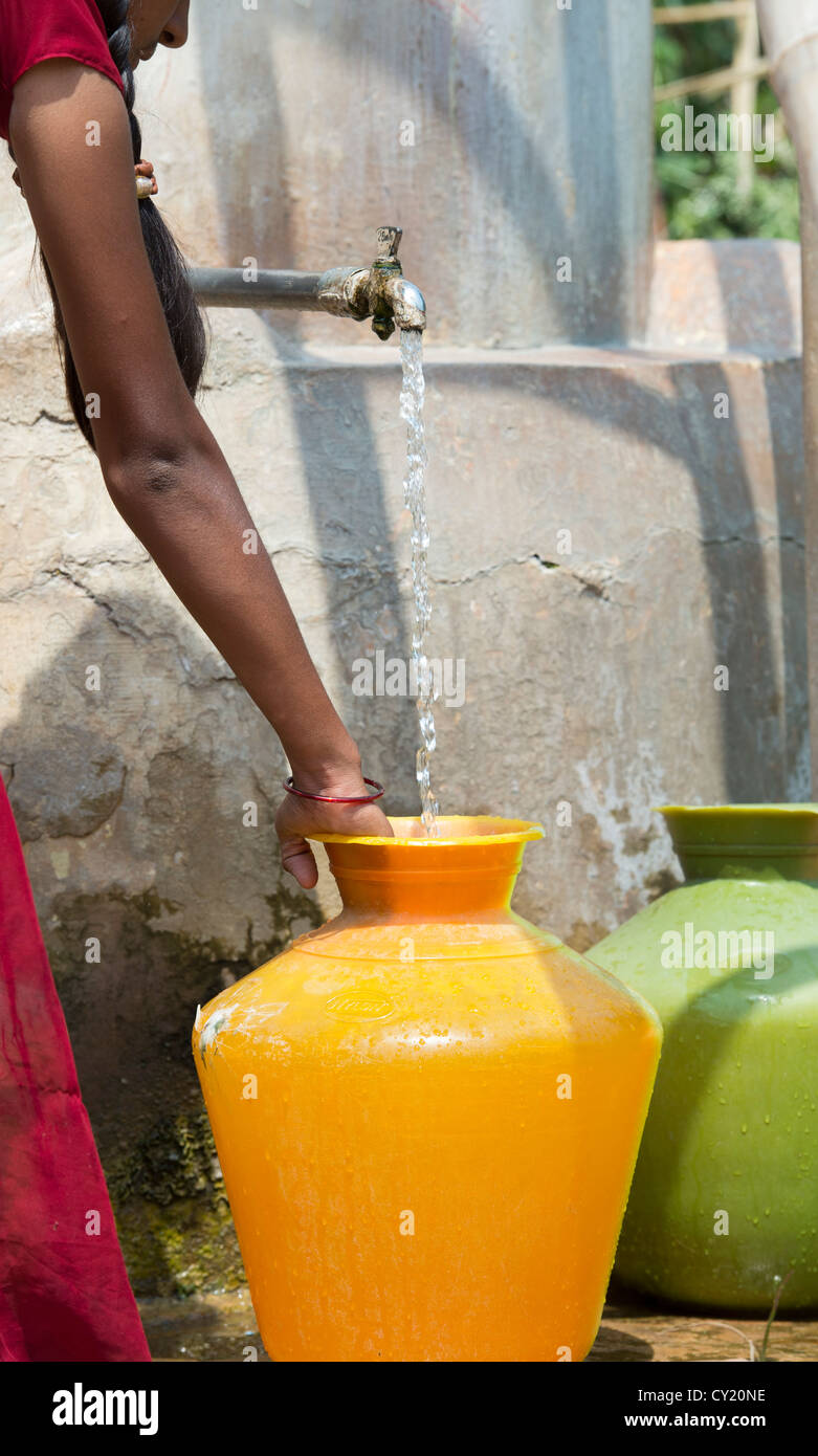Rural Indian village girl collecting water from a communal water tank. Andhra Pradesh, India Stock Photo