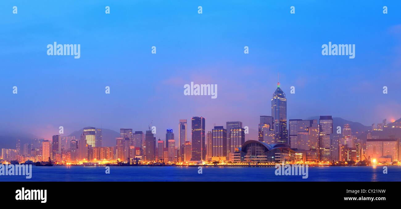 Hong Kong Victoria Harbor morning with urban skyscrapers over sea with blue tone and street light. Stock Photo