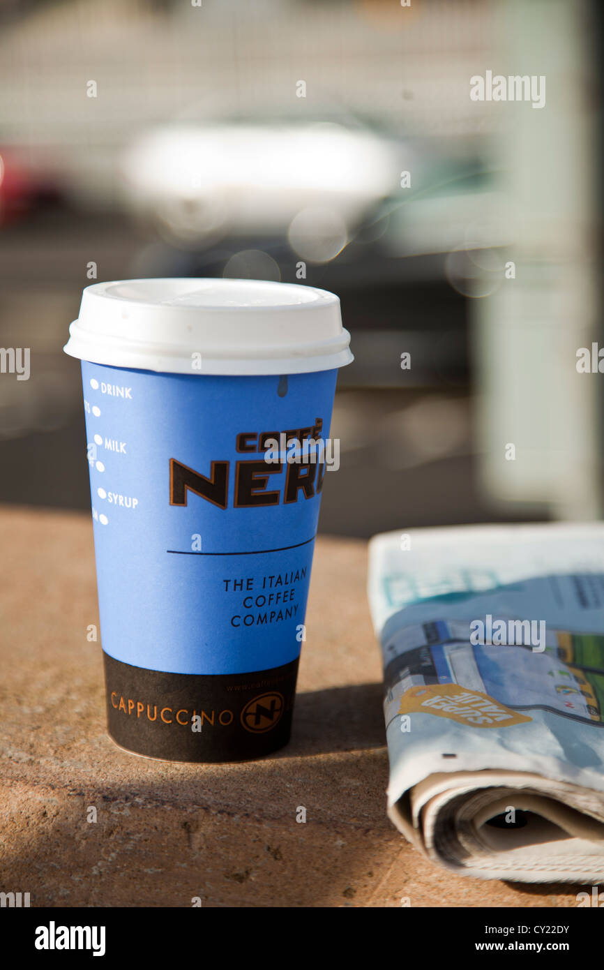 Take away out cup of latte cappuccino coffee from Caffe Nero with news