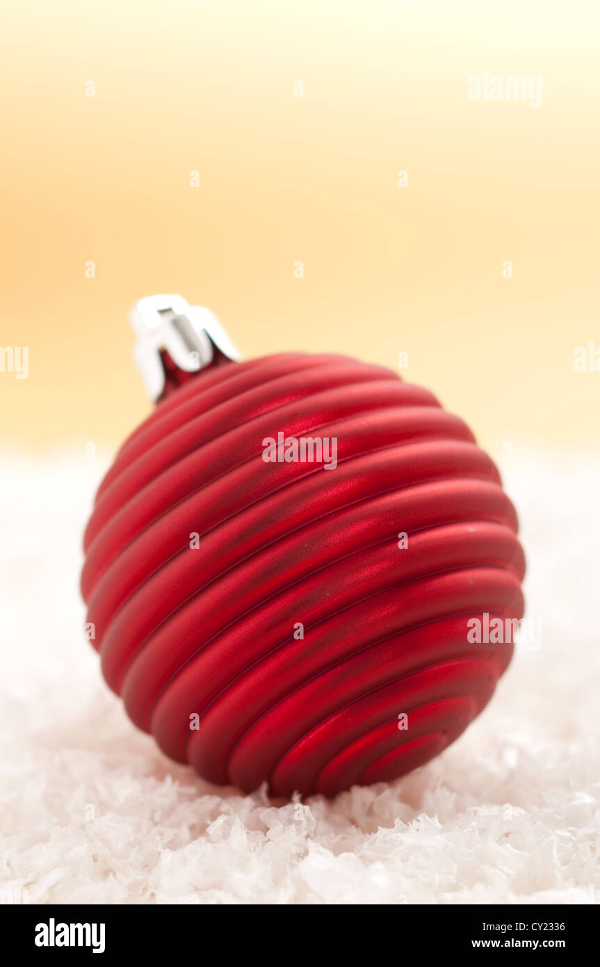 Red christmas ornament in the snow with gold background Stock Photo - Alamy