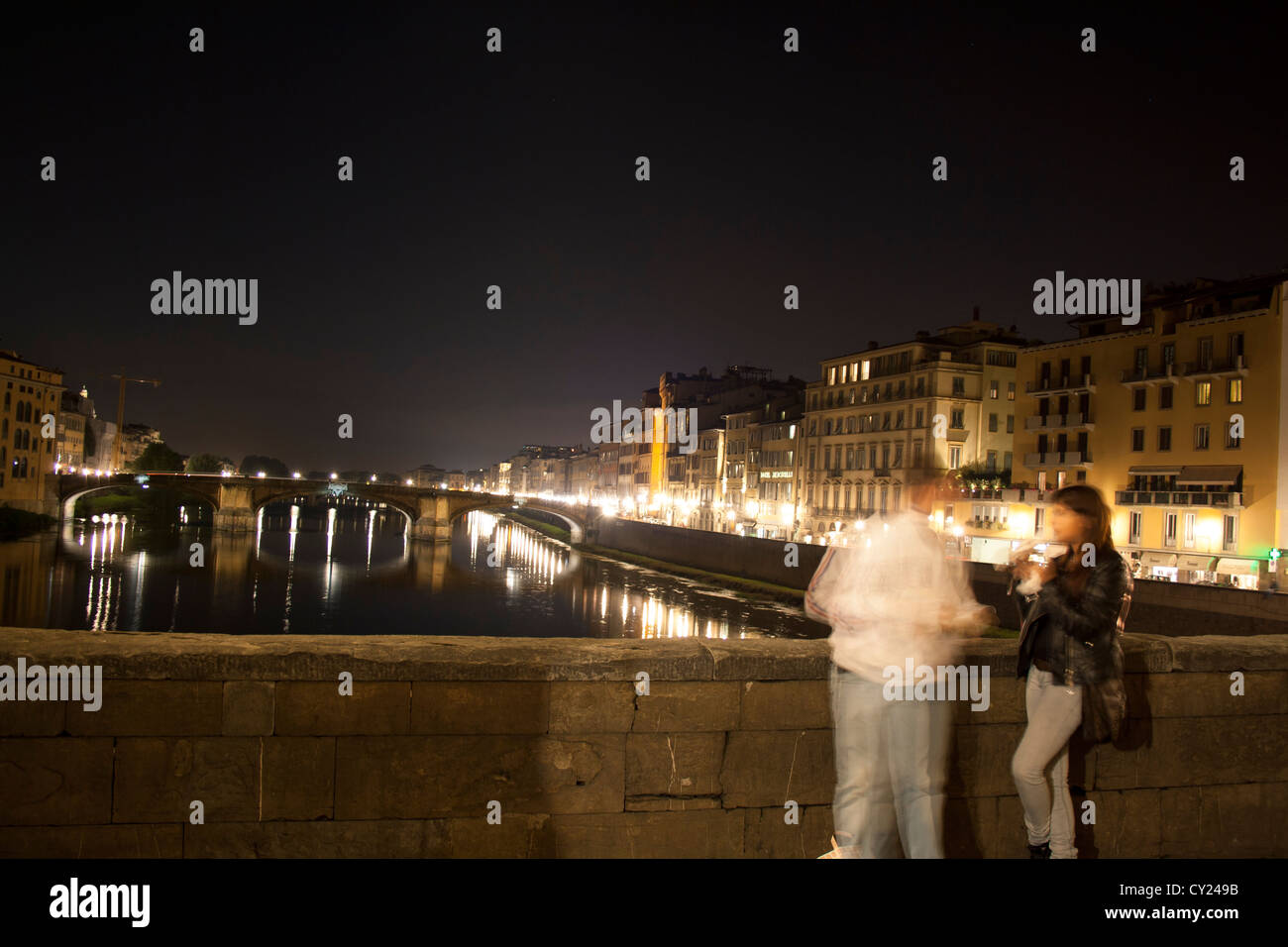 Tourists chatting on Ponte Vecchio with a view along the Arno river in the historic centre of Florence, Italy Stock Photo