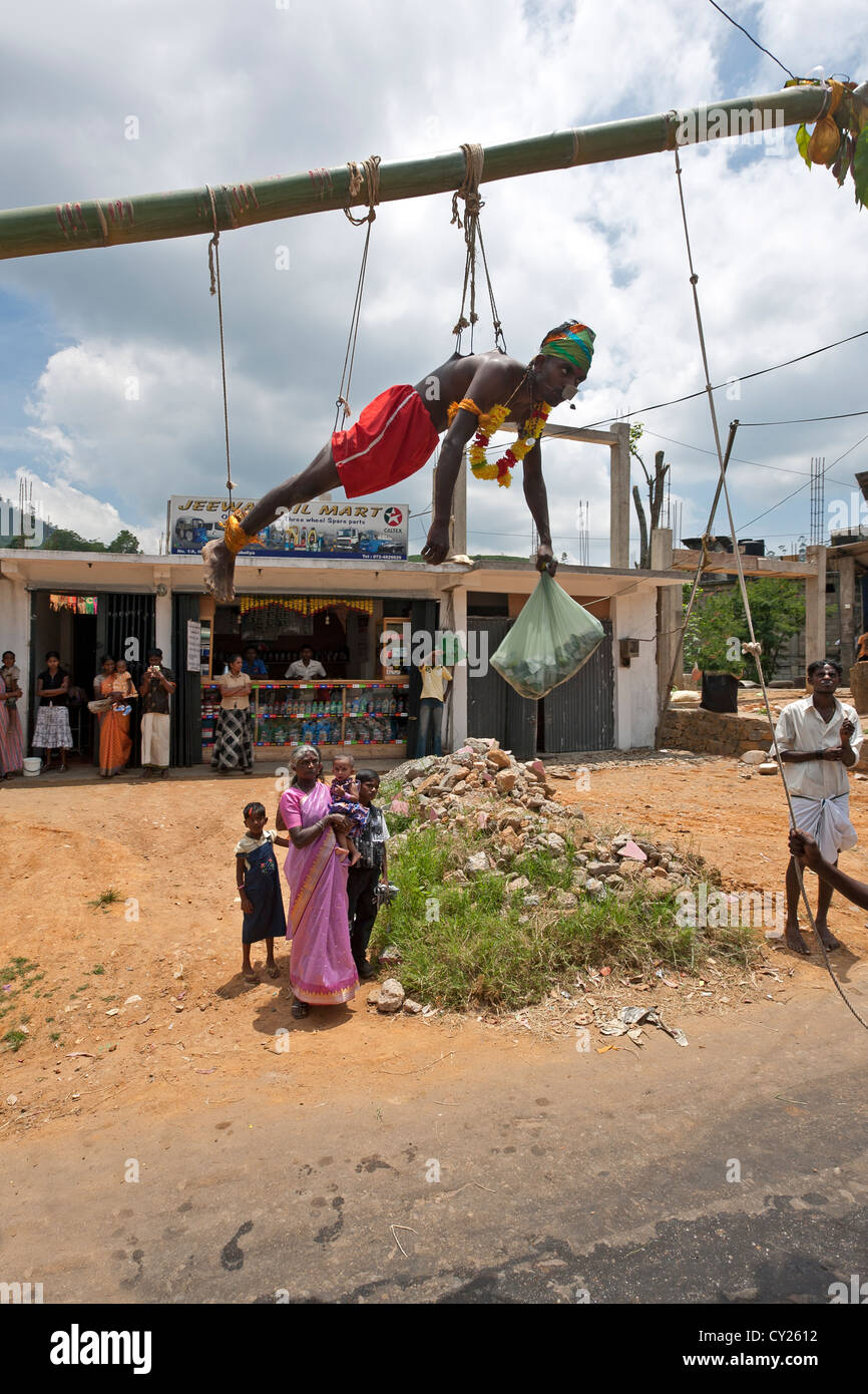 Man hanging on hooks pierced into his body. Tamil religion ritual Stock