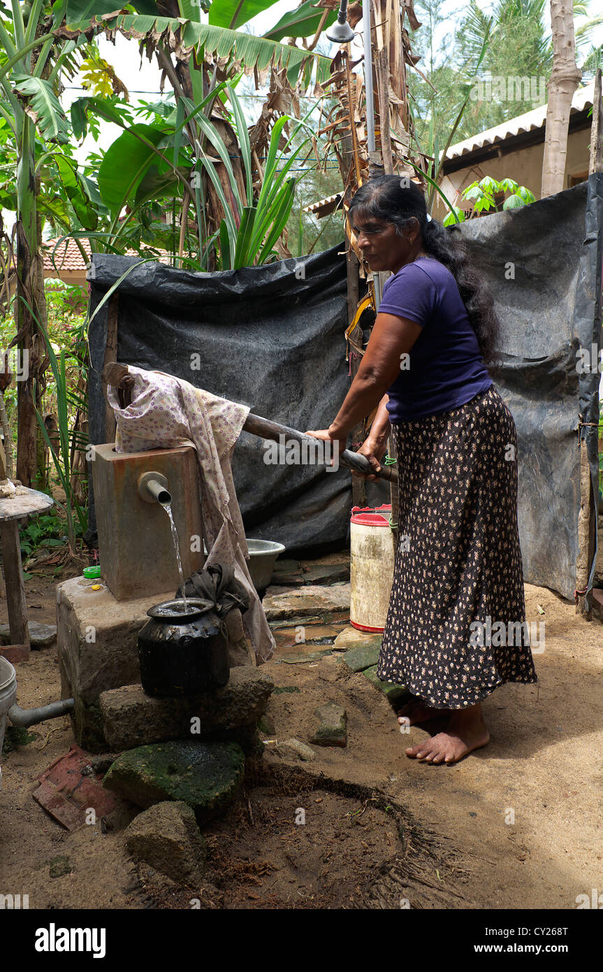 Adult woman from Waikkal village, getting water from a water well using an old hand operated pump, Waikkal Village, Sri Lanka, Stock Photo