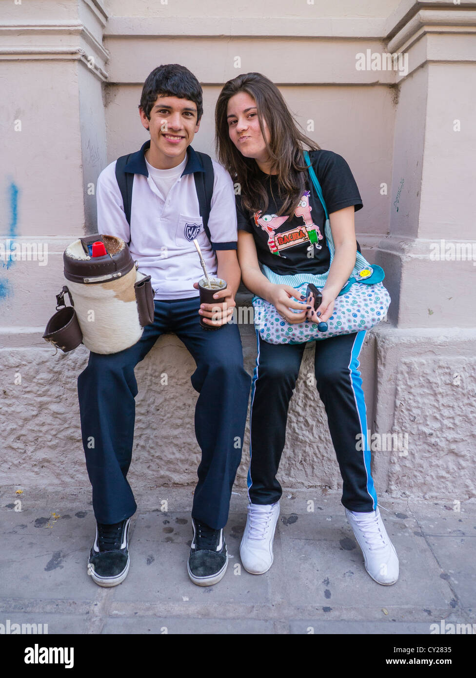 A boy and girl Paraguayan high school students sit outside of their school during lunch break posing for a photograph. Stock Photo