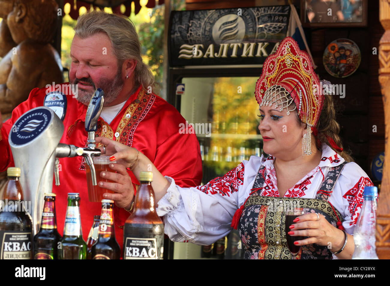 During a festival Ukrainian people in traditional costumes serving beer from Eastern Europe behind a beverage stand. Stock Photo