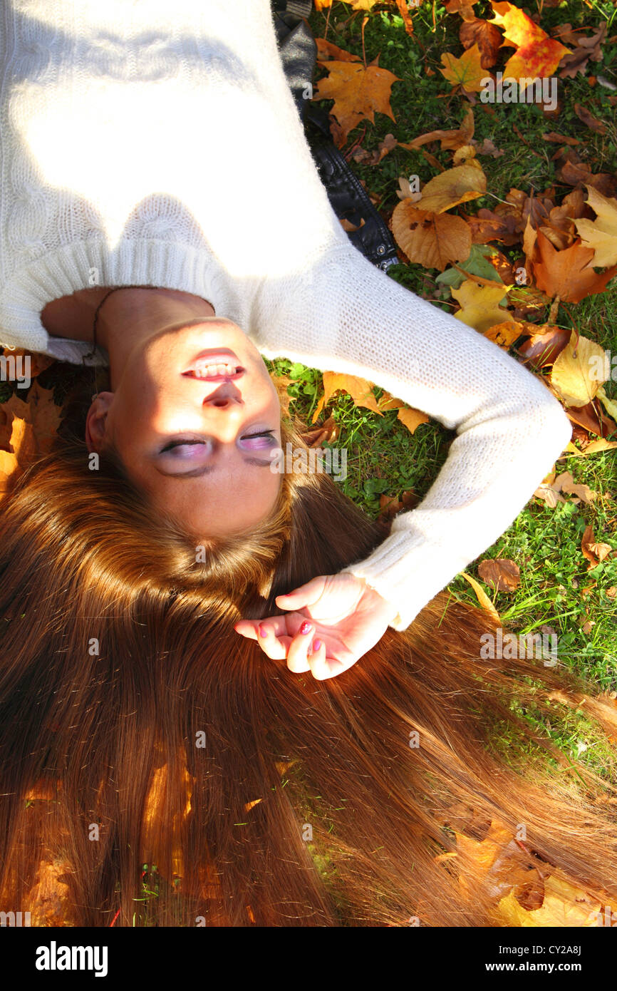 Young woman with autumn leaves in hand and fall yellow maple garden ...