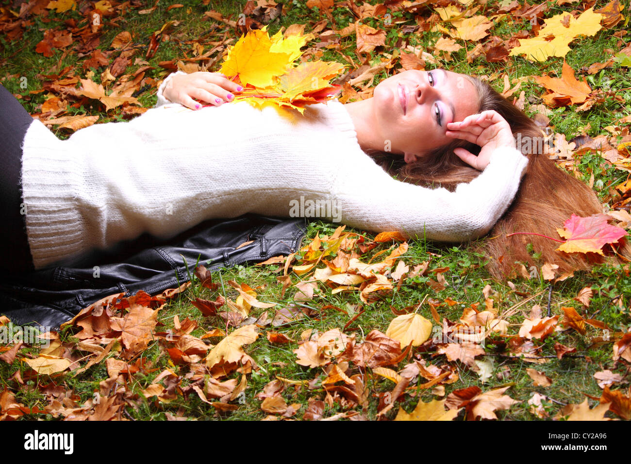 Young woman with autumn leaves in hand and fall yellow maple garden ...