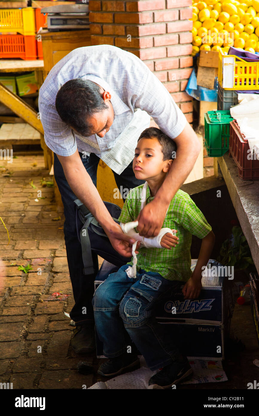 Father wrapping arm of injured son in Marche Central in Tunis, Tunisia Stock Photo