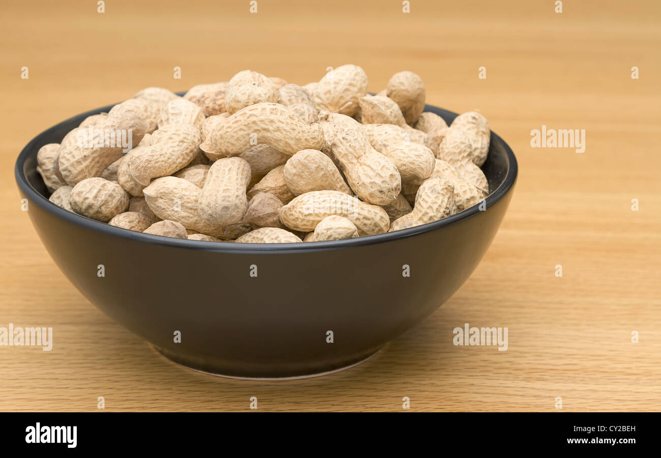 Peanuts in a black bowl on table Stock Photo