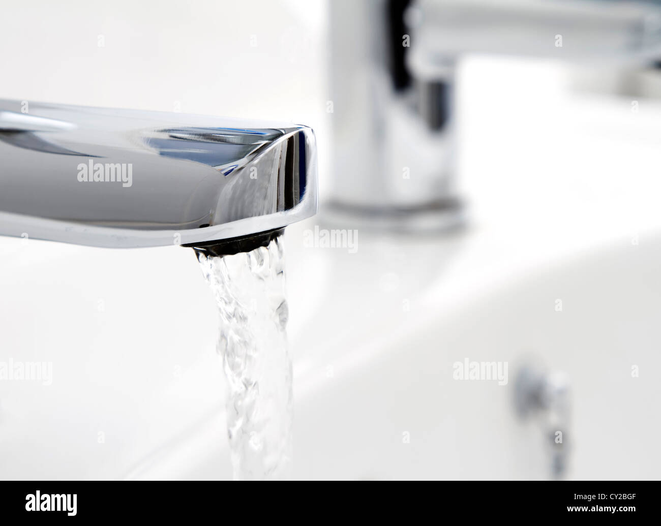 Water flowing from tap into basin Stock Photo