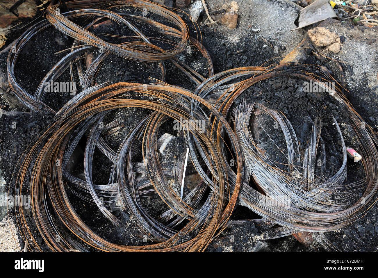 Steel wire remains of burnt out vehicle tires on Sri Lankan beach Stock