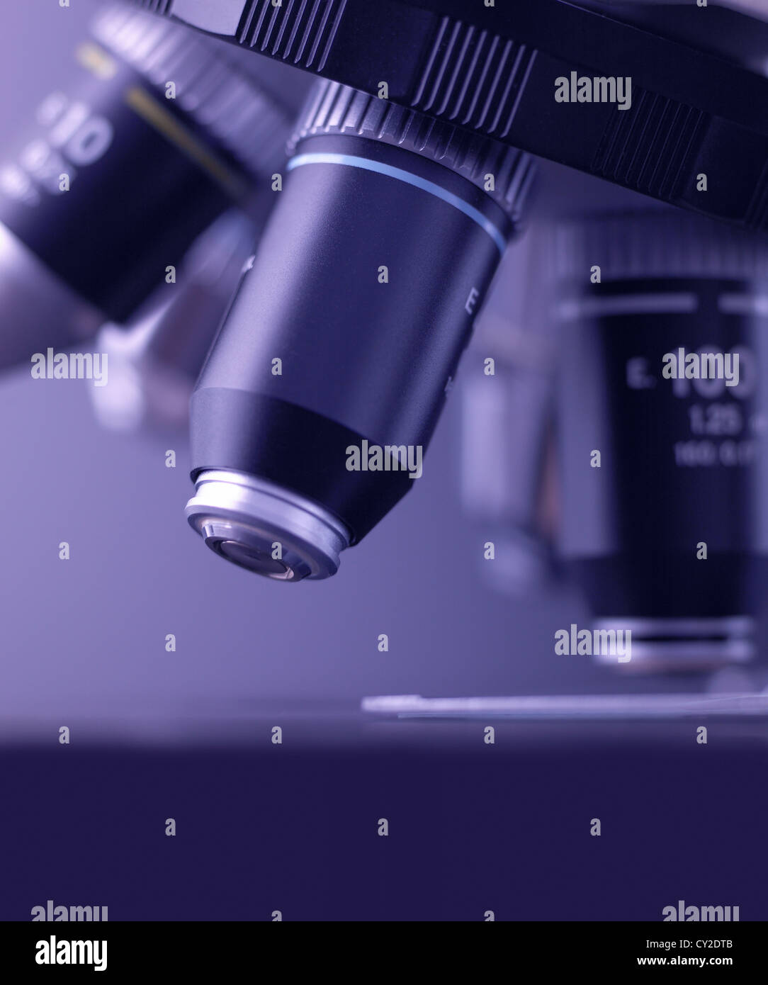 Lenses on the turret of a research microscope with glass slide on stage