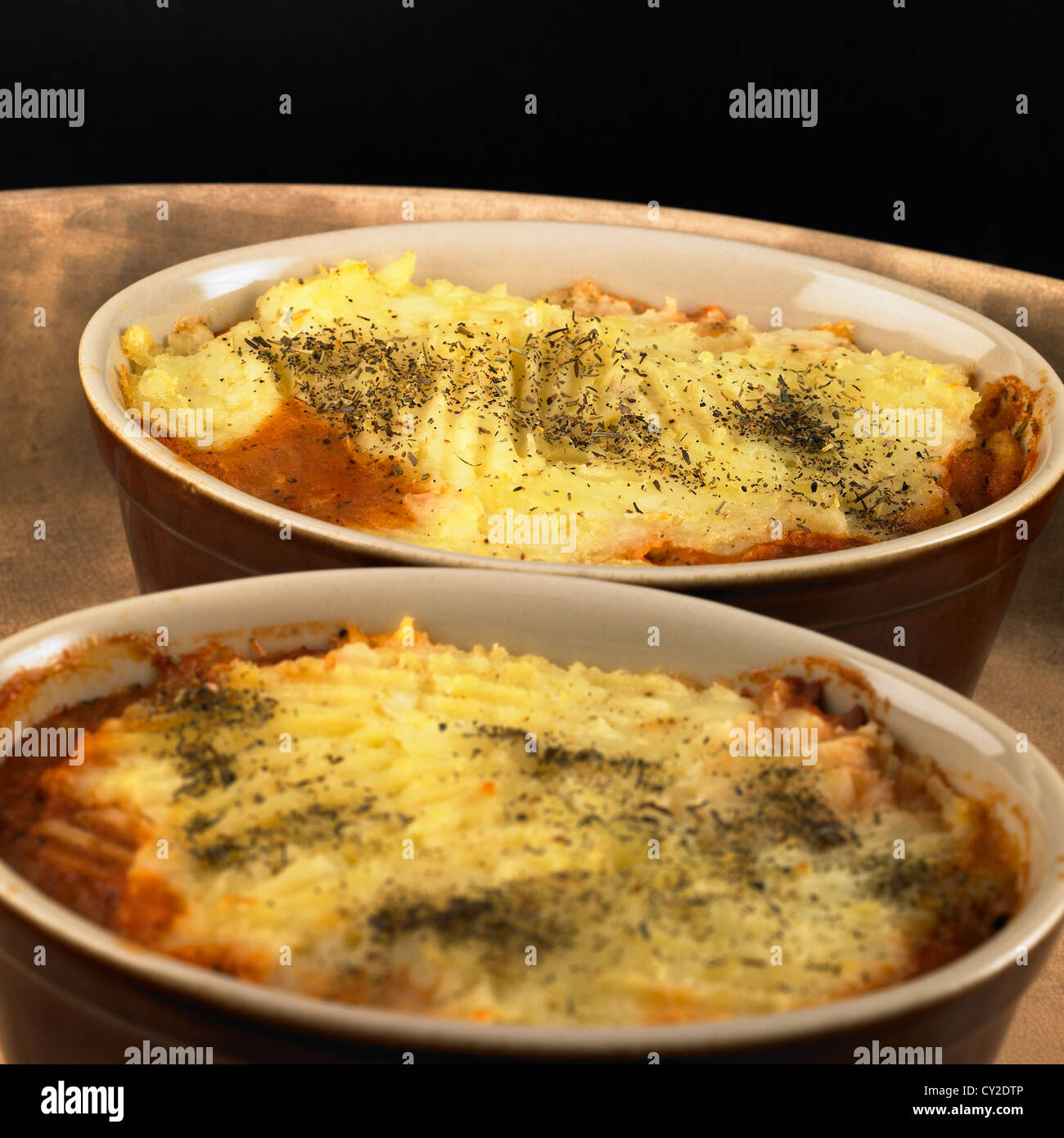 Autumn and winter food. Individual handmade beef and bean casseroles topped with herb potato Stock Photo