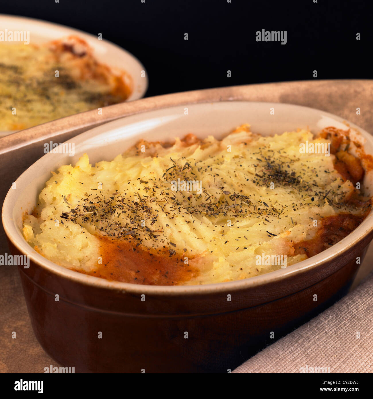 Autumn and winter food. Individual handmade beef and bean casseroles topped with herb potato Stock Photo