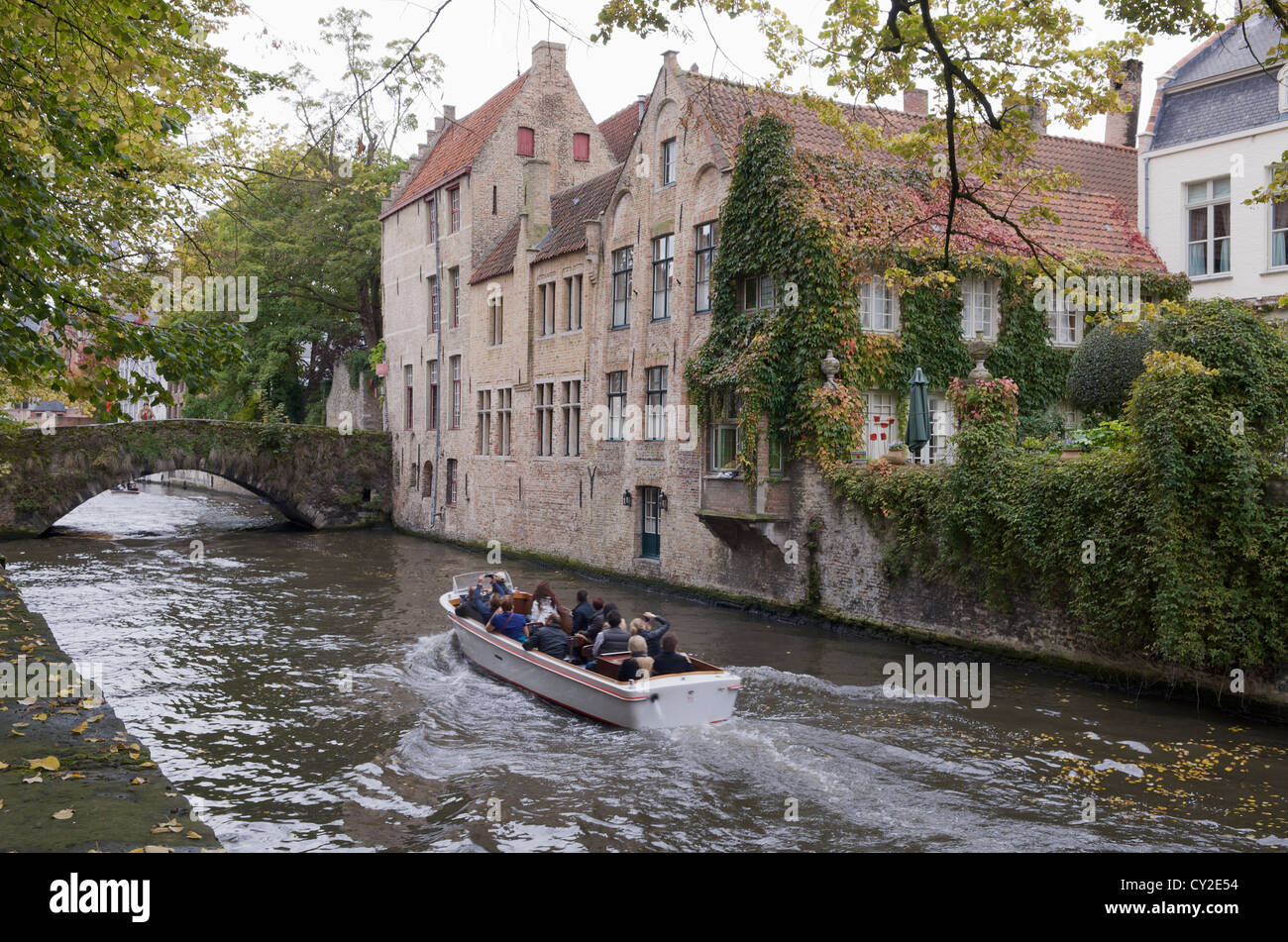 Tourists enjoying a boat trip on a beautiful canal in the Belgian city of Brugge Stock Photo