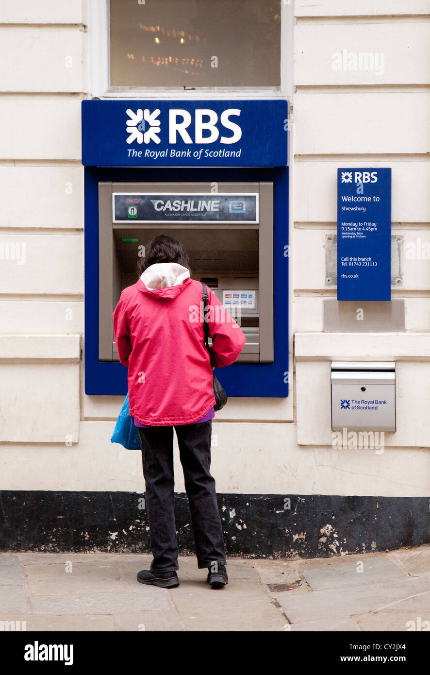 A woman getting cash money from an RBS Royal Bank of Scotland ATM cash machine Shrewsbury UK Stock Photo