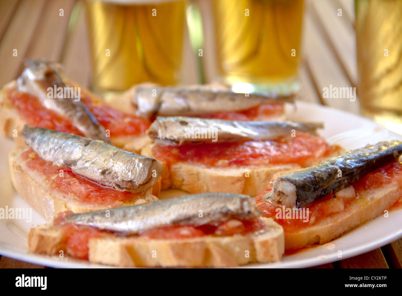 Spanish tapas of bread with tomato paste and sardines, with beers in