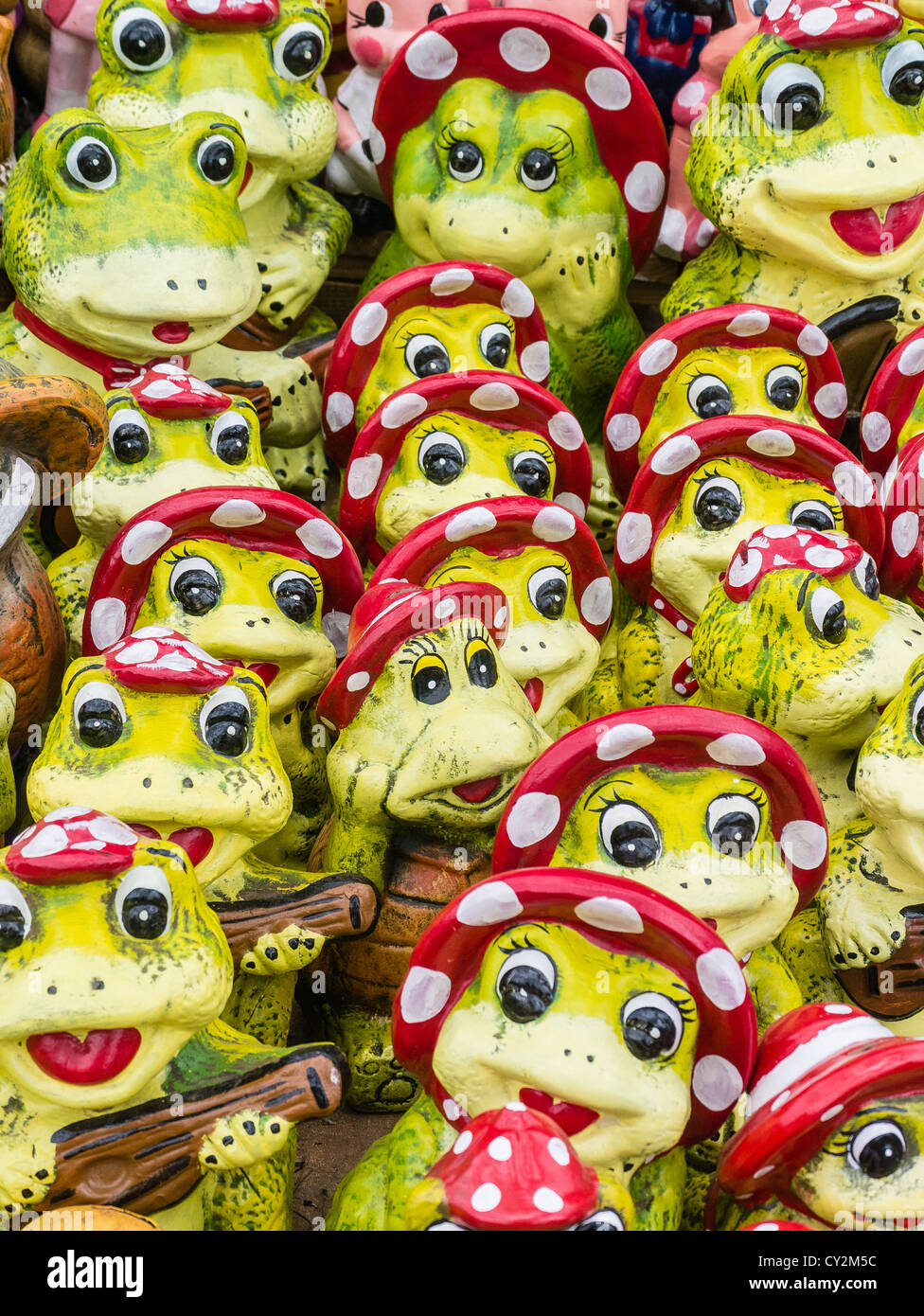 Kitsch lawn art for sale in the form of yellow-green frogs wearing red bonnets at a street market in Asunción Paraguay. Stock Photo