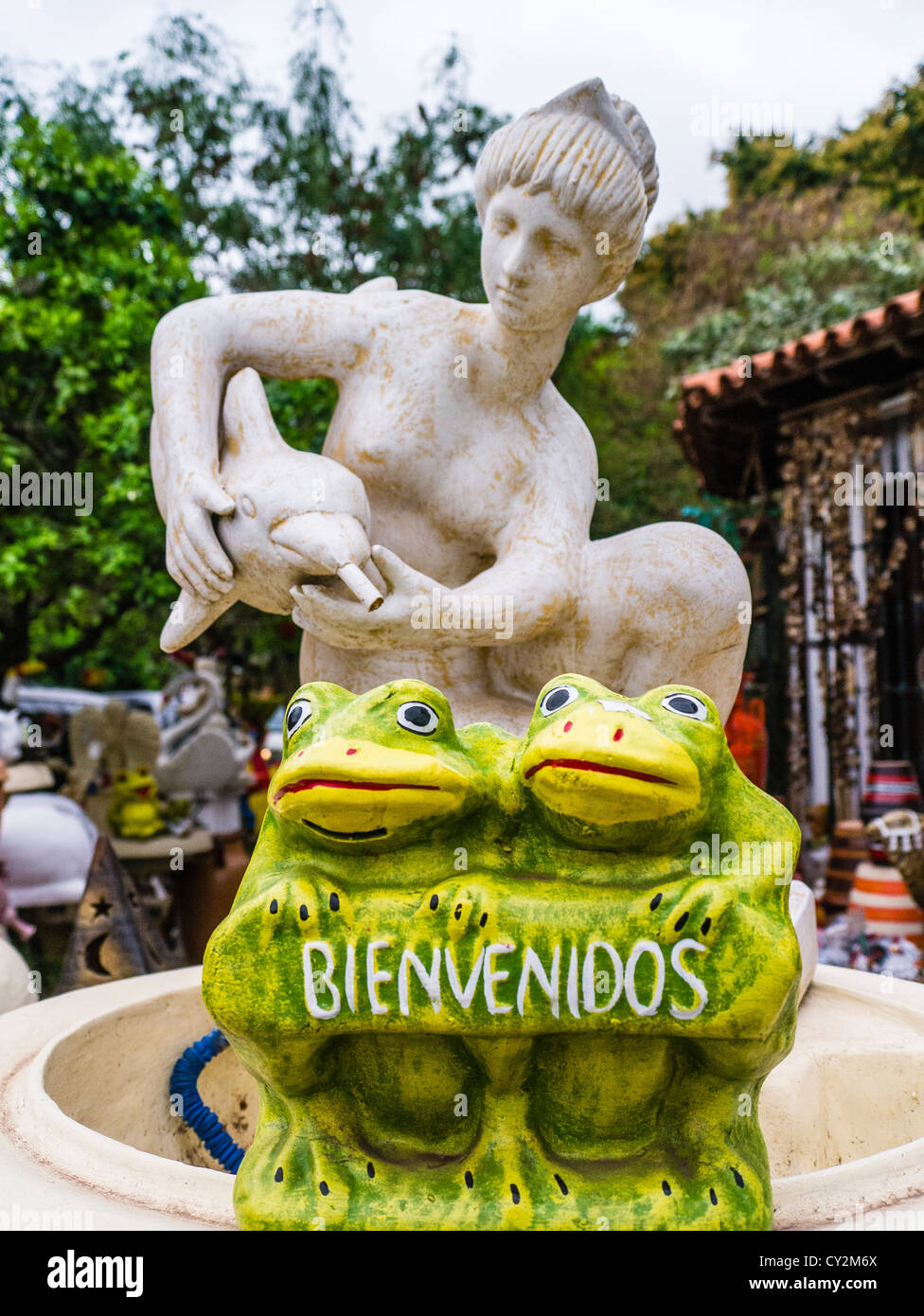 Kitsch lawn art in form of a woman figurine holding dolphin and two frogs for sale at a street market in Asunción Paraguay. Stock Photo