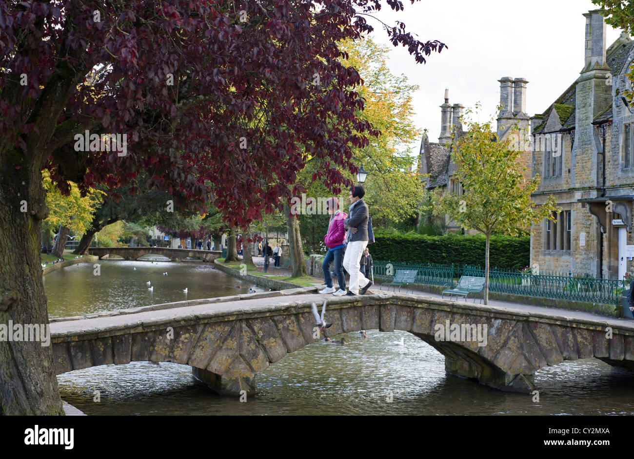 Cotswold village of Bourton-on-the-water with  tourists crossing the bridge over the river Windrush, Gloucestershire, England Stock Photo