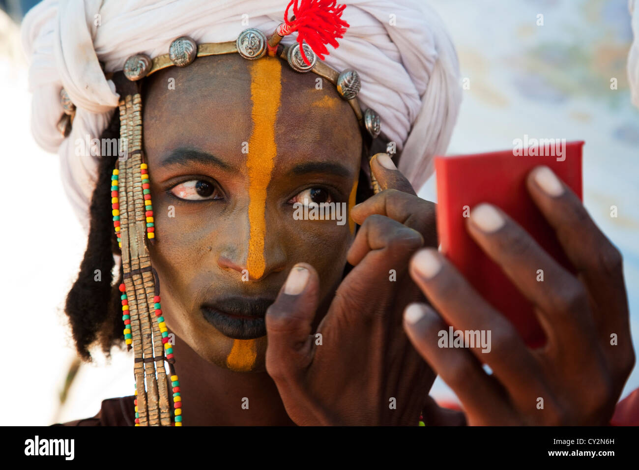 Wodaabe man is putting on make up in preparation for dancing at the geerewol festival in northern Niger, Africa Stock Photo