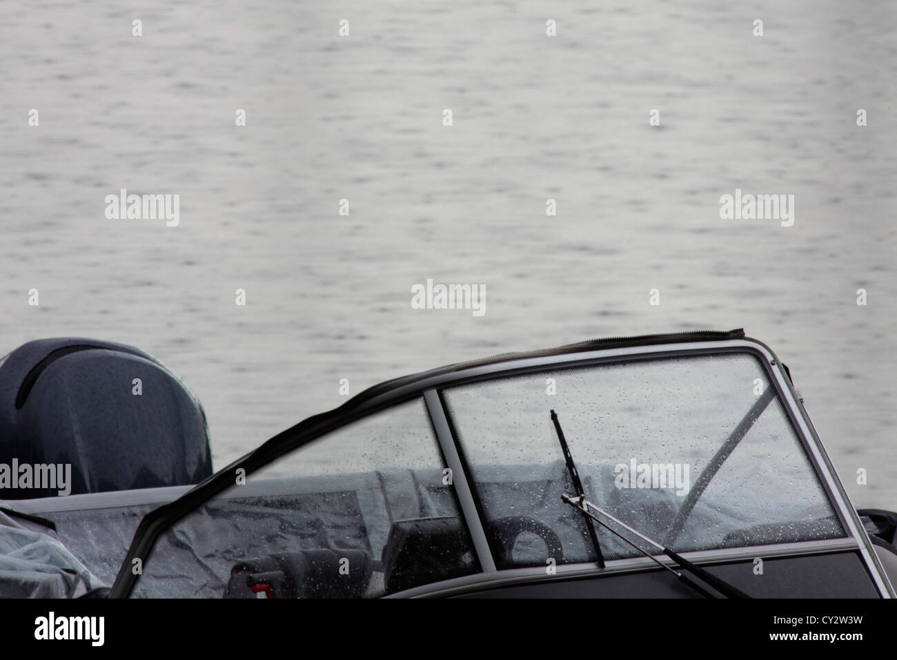 Rain is splattering on the windscreen of an open motorboat. Stock Photo