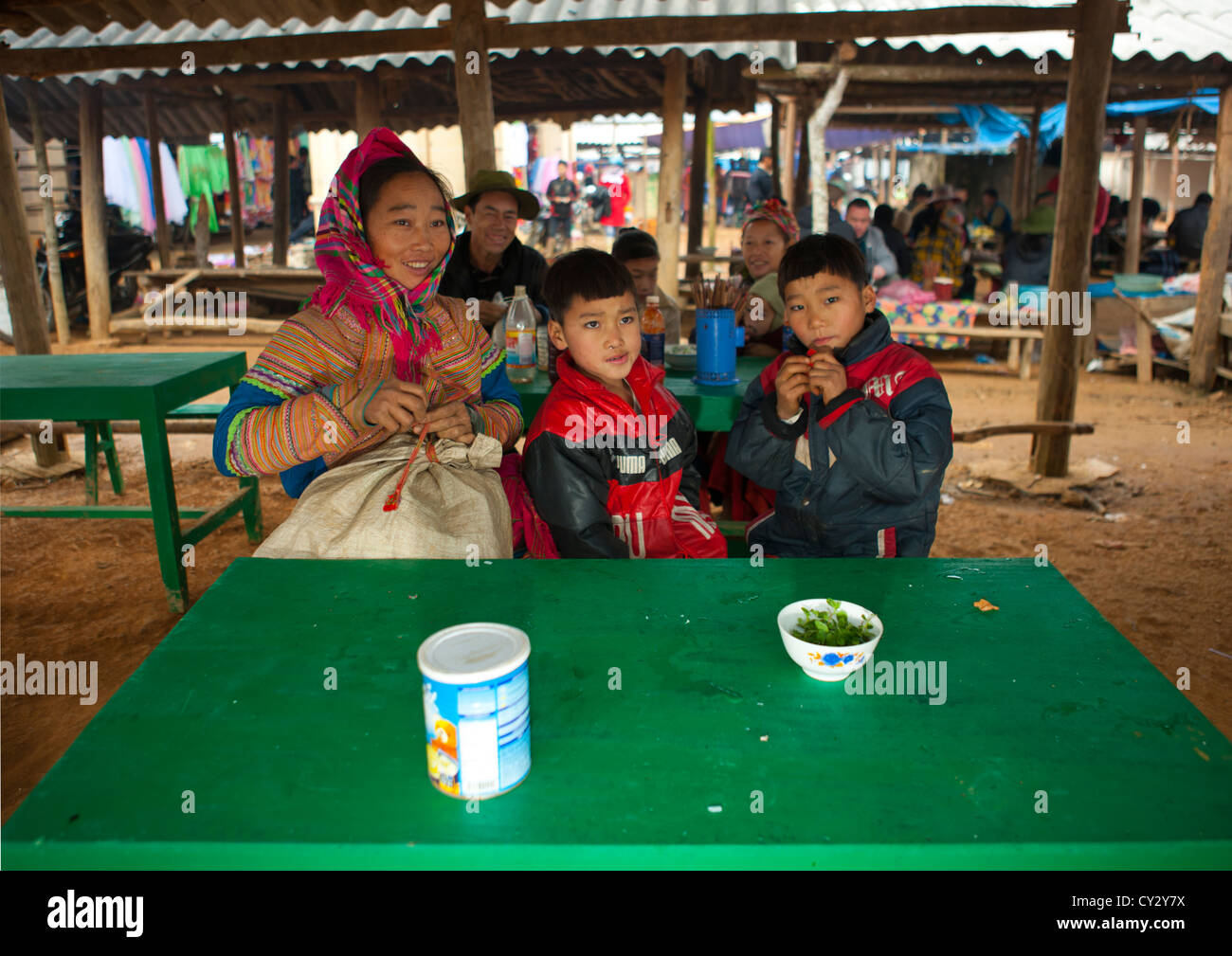 Flower Hmong Woman And Her Sons Sitting On A Table For Lunch, Sapa Market, Vietnam Stock Photo