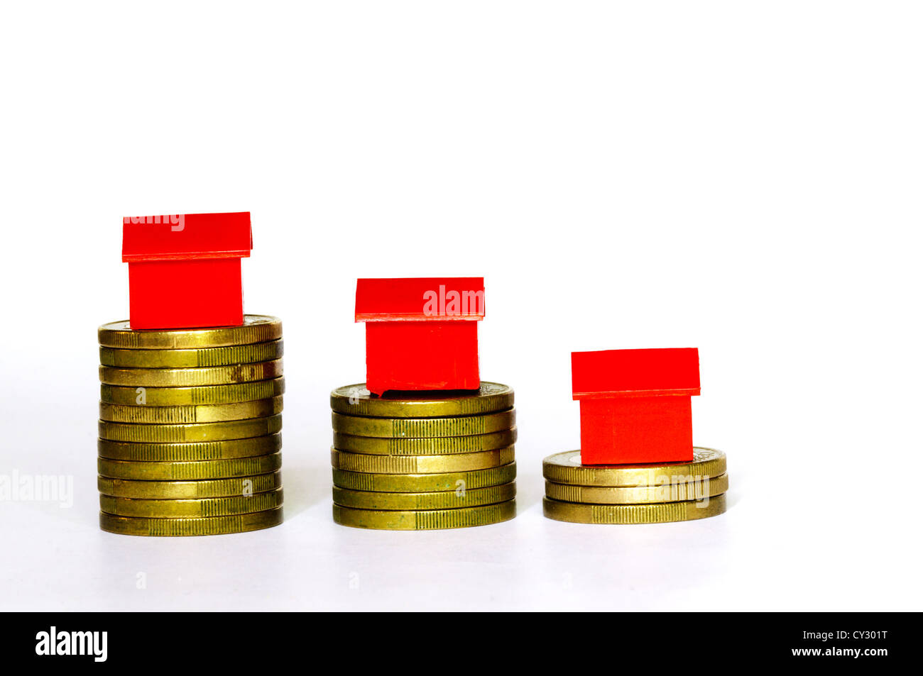 Plastic model houses balanced on top of stacks of coins. Stock Photo