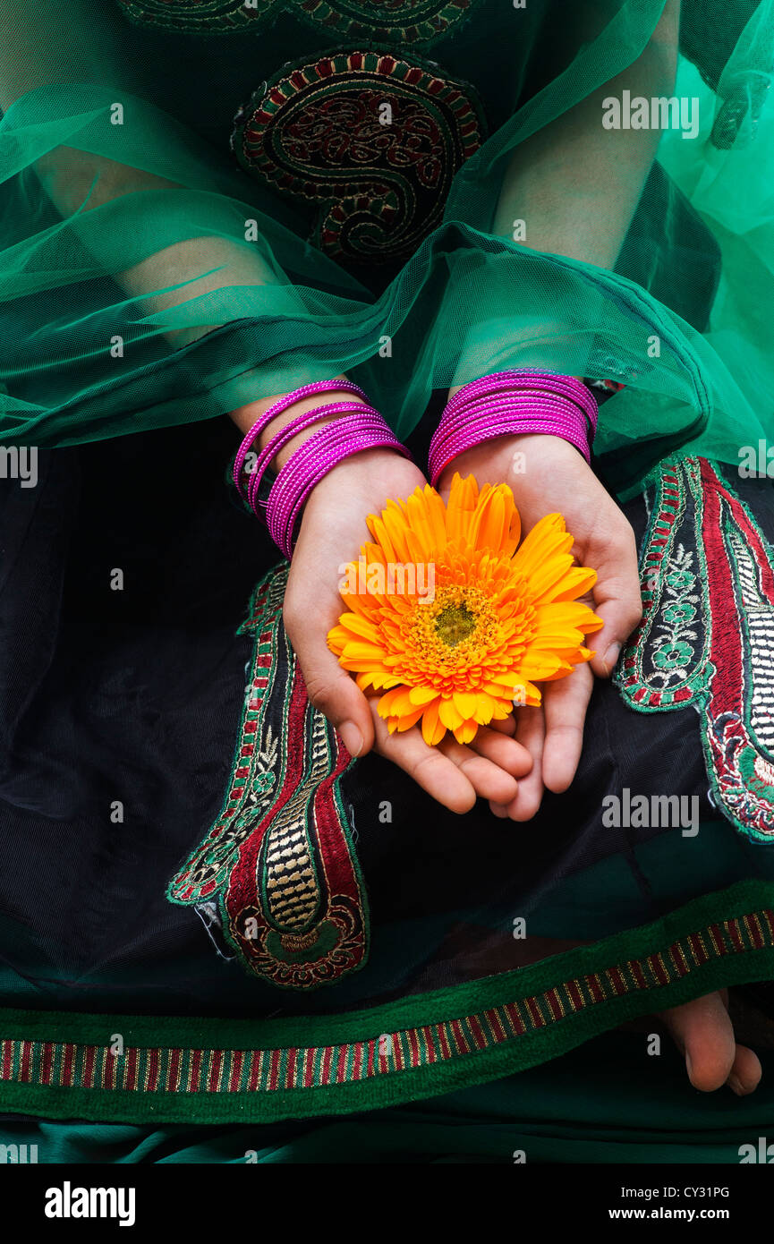 Indian girl with green veil holding an orange gerbera flower in her hands. Andhra Pradesh, India Stock Photo
